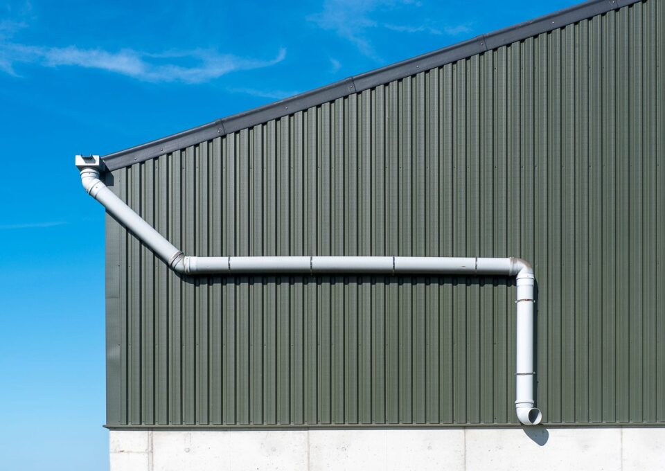 Steel-clad building wall with a downspout for roof drainage